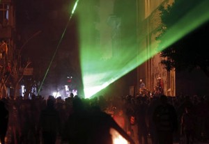 Protesters opposing Egyptian President Mursi shout slogans and shine laser pointers at riot police during clashes in Cairo